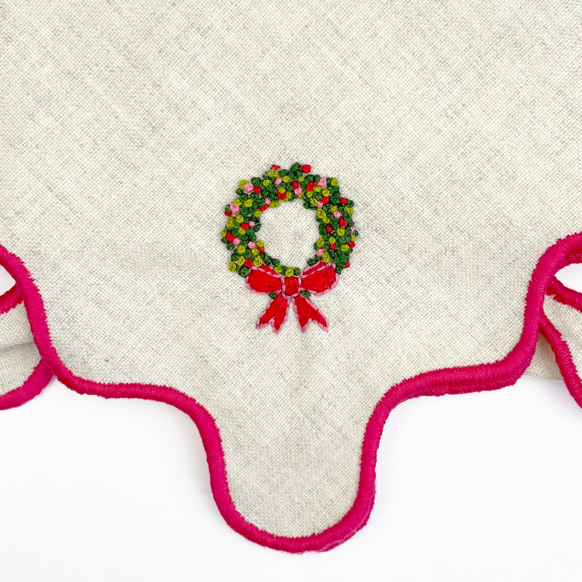 Embroidered Christmas wreath with red bow on a white fabric background