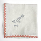Fabric with embroidered design of a pea pod and the word 'peas' on a white background.