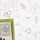 Set of autumn or fall themed embroidery patterns on a pink background with fabric and scissors.