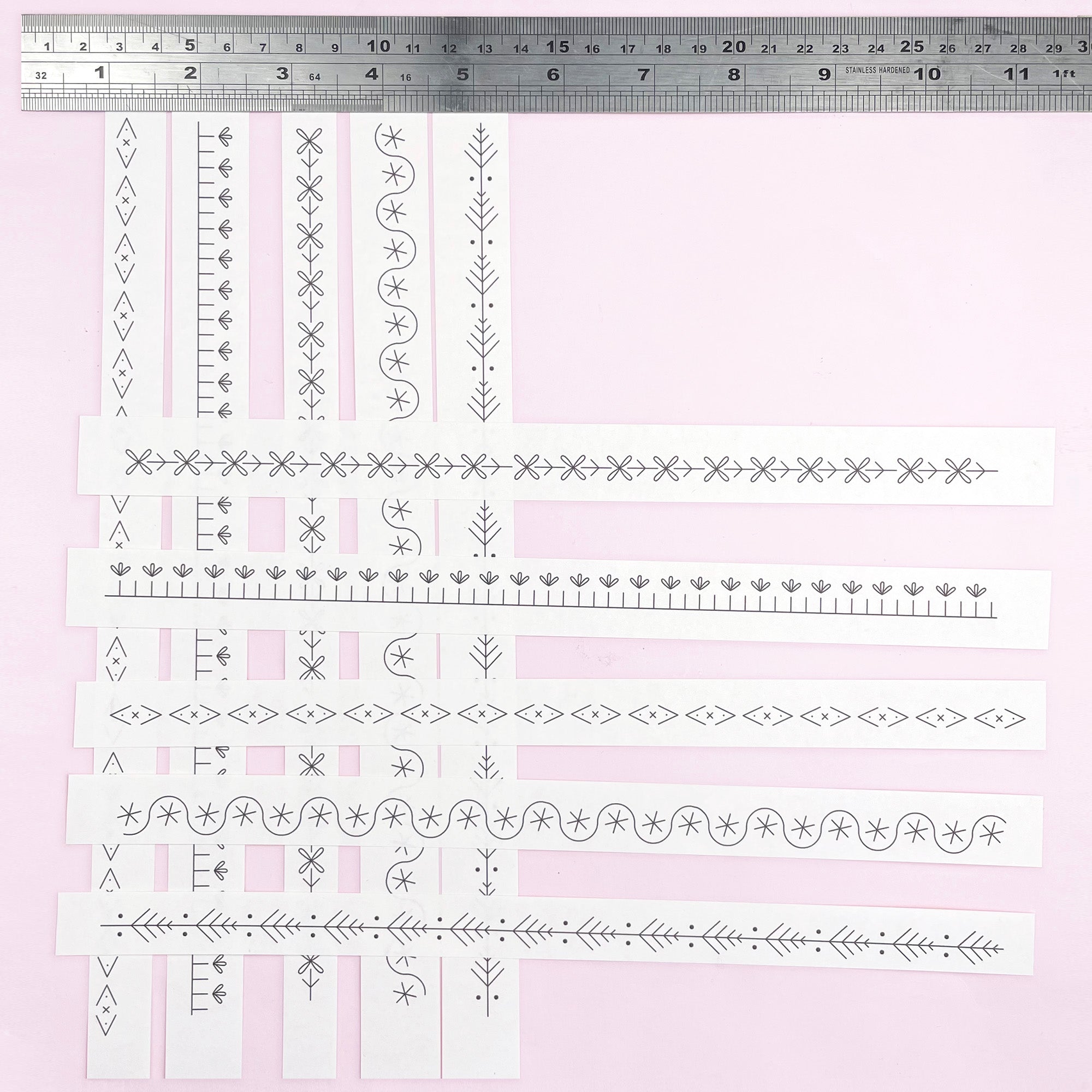 Set of decorative border designs on a pink background with a ruler at the top.