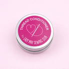 Thread festive conditioner container with pink label on a light pink background
