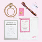 Embroidery kit with wooden hoops, colorful threads, instructional booklet, stitch marker, and storage pouch on light background