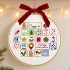 A round embroidery hoop advent calendar hanging from a red ribbon bow, featuring colorful Christmas-themed stitched icons and the words 'Merry Christmas' on a cream fabric background, with warm string lights blurred in the background.