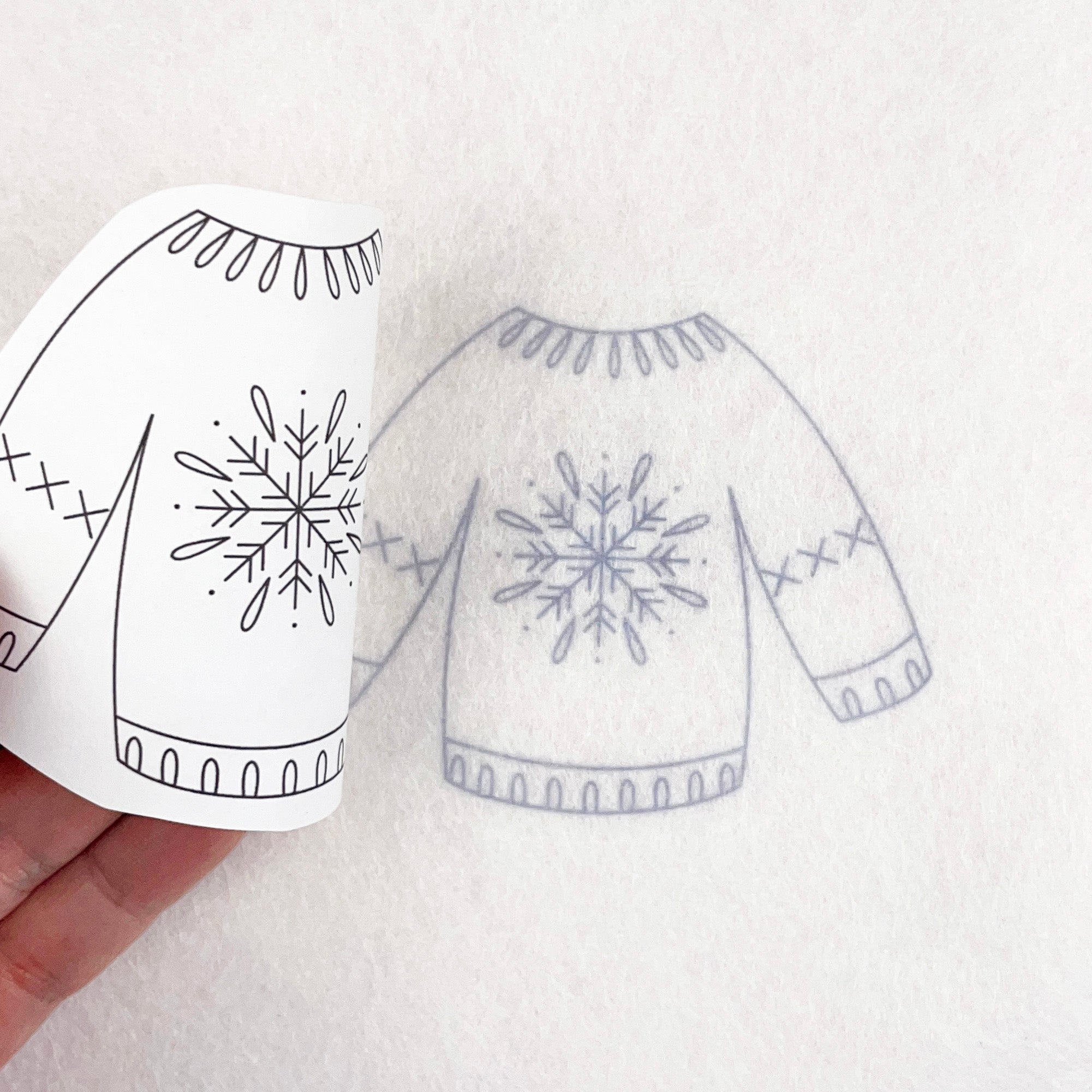 iron on transfer of a christmas jumper being transferred on to white fabric ready for stitching.