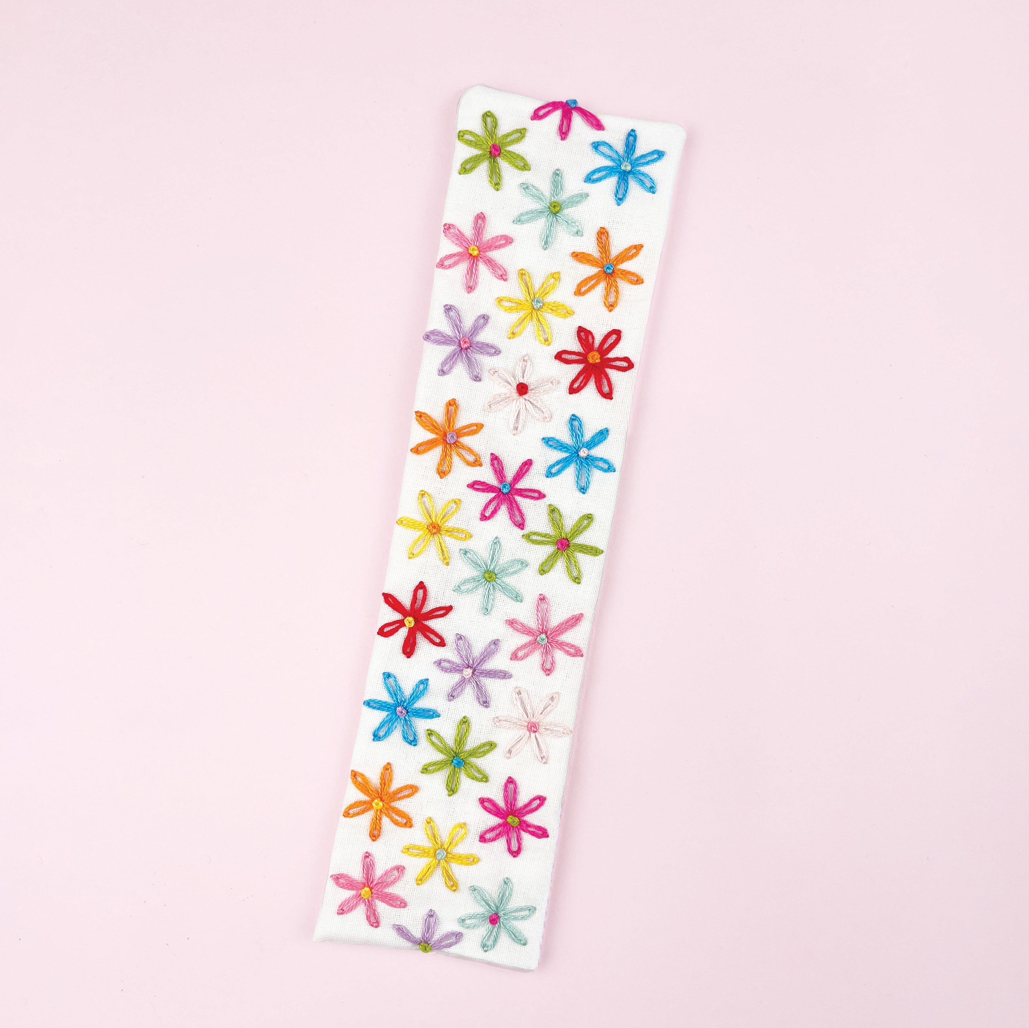 Colorful flower-patterned bookmark on a pink background
