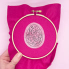 Easter egg embroidery pattern applied to bright pink fabric in a hoop. A dissolving stick and stitch embroidery design for Easter crafting.