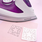 Iron-on Easter embroidery pattern being transferred onto pink fabric with a steam iron. A simple and effective technique for creating beautiful Easter embroidery designs.