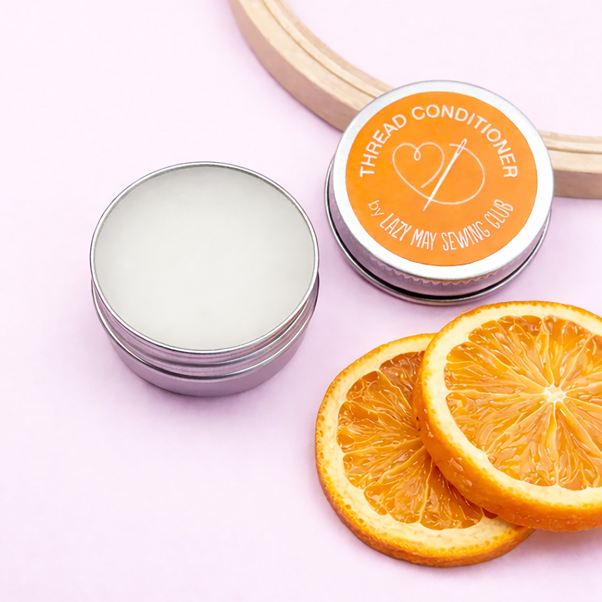 Thread conditioner container with orange slices on a pink background