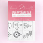 Cover of 'Lazy May Sewing Club' with embroidery patterns on a pink and white background