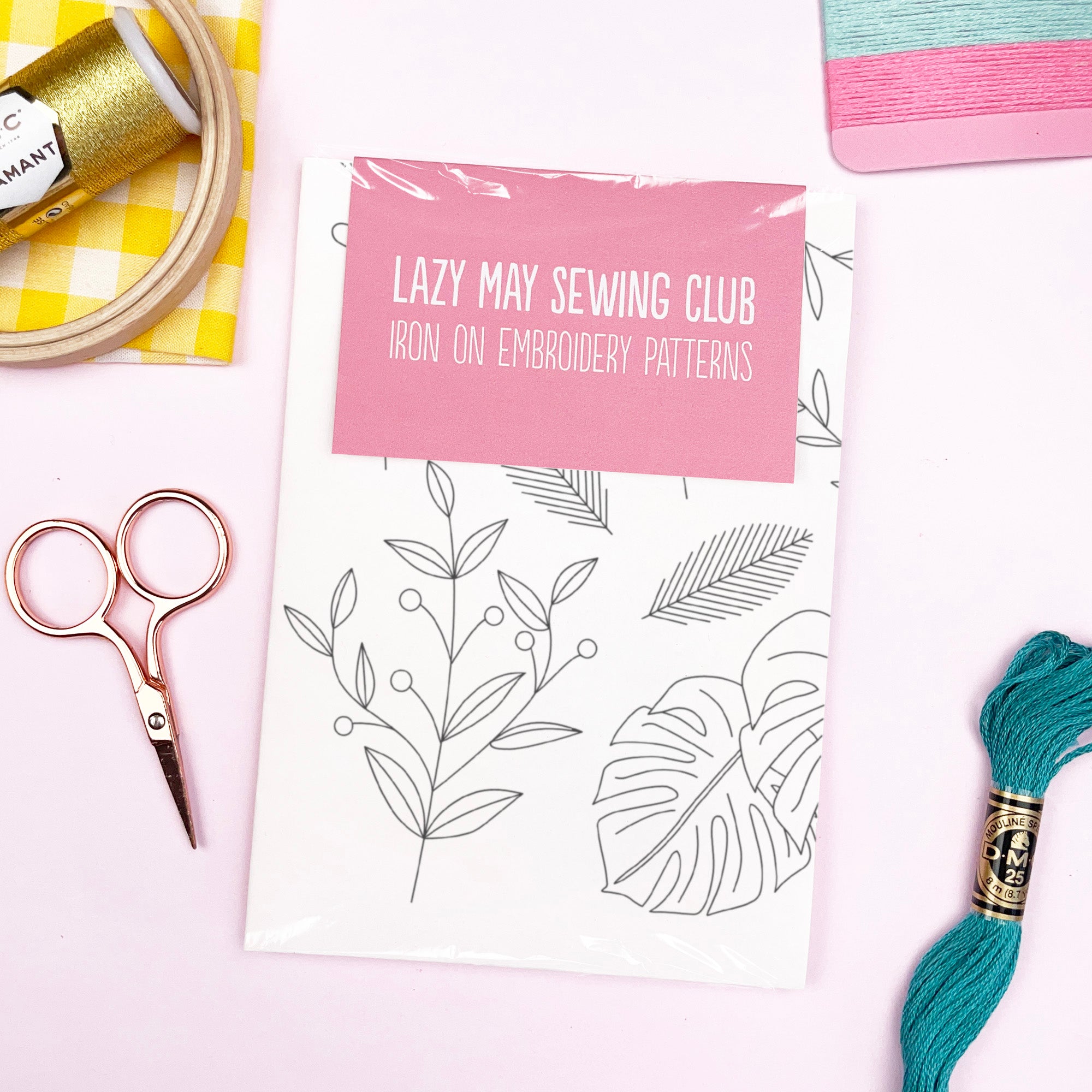 Lazy May Sewing Club iron on embroidery patterns with sewing tools on a white background