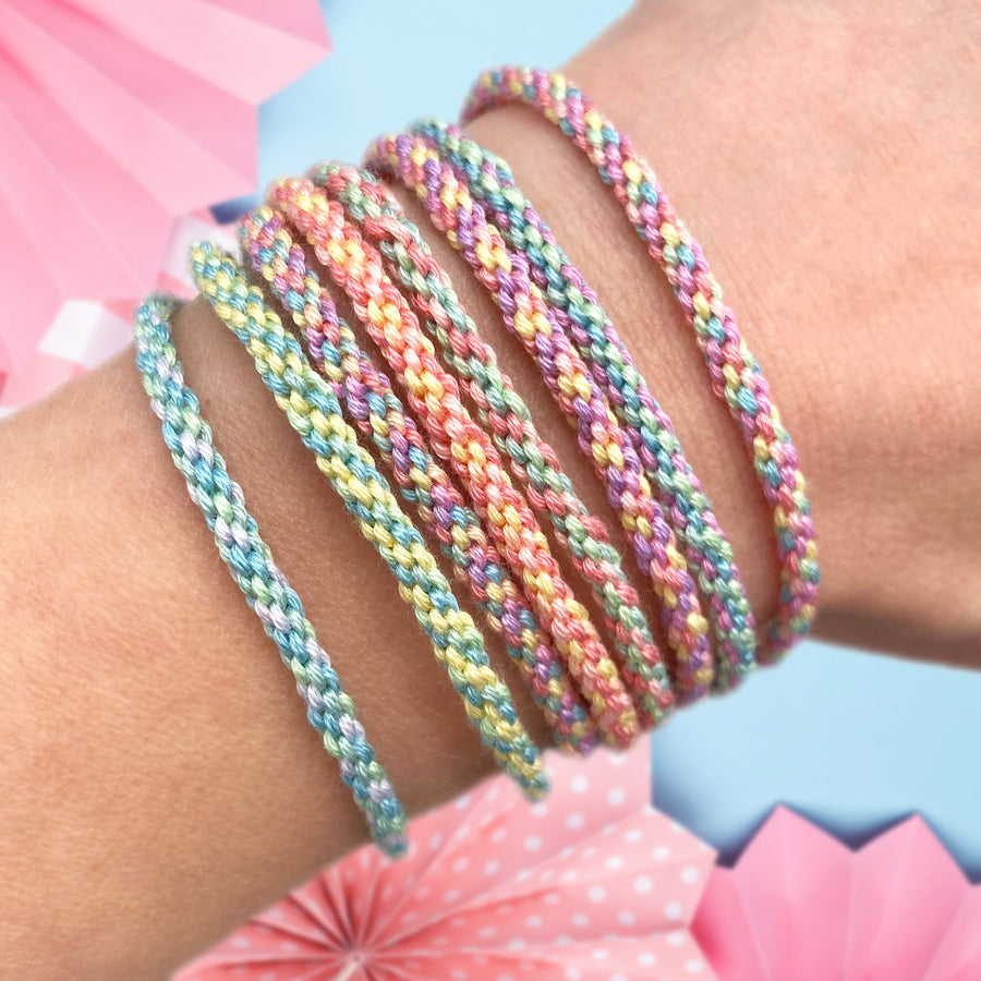 pastel woven friendship bracelets on a wrist with soft coloured threads