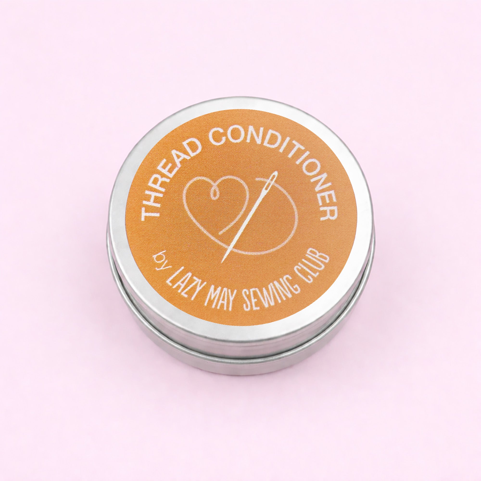 Thread conditioner tin with Lazy May Sewing Club branding on a pink background