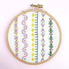 Embroidery hoop with colorful geometric patterns on a white background. example of border designs from iron on embroidery patterns