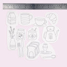 Set of iron on embroidery transfer patterns of kitchen items on a light pink background with a ruler at the top.