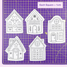 Five gingerbread house-shaped embroidery patterns on a purple cutting mat with grid lines.