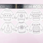 Set of six black and white sweaters embroidery pattern designs with patterns on a light pink background, accompanied by a ruler for scale.