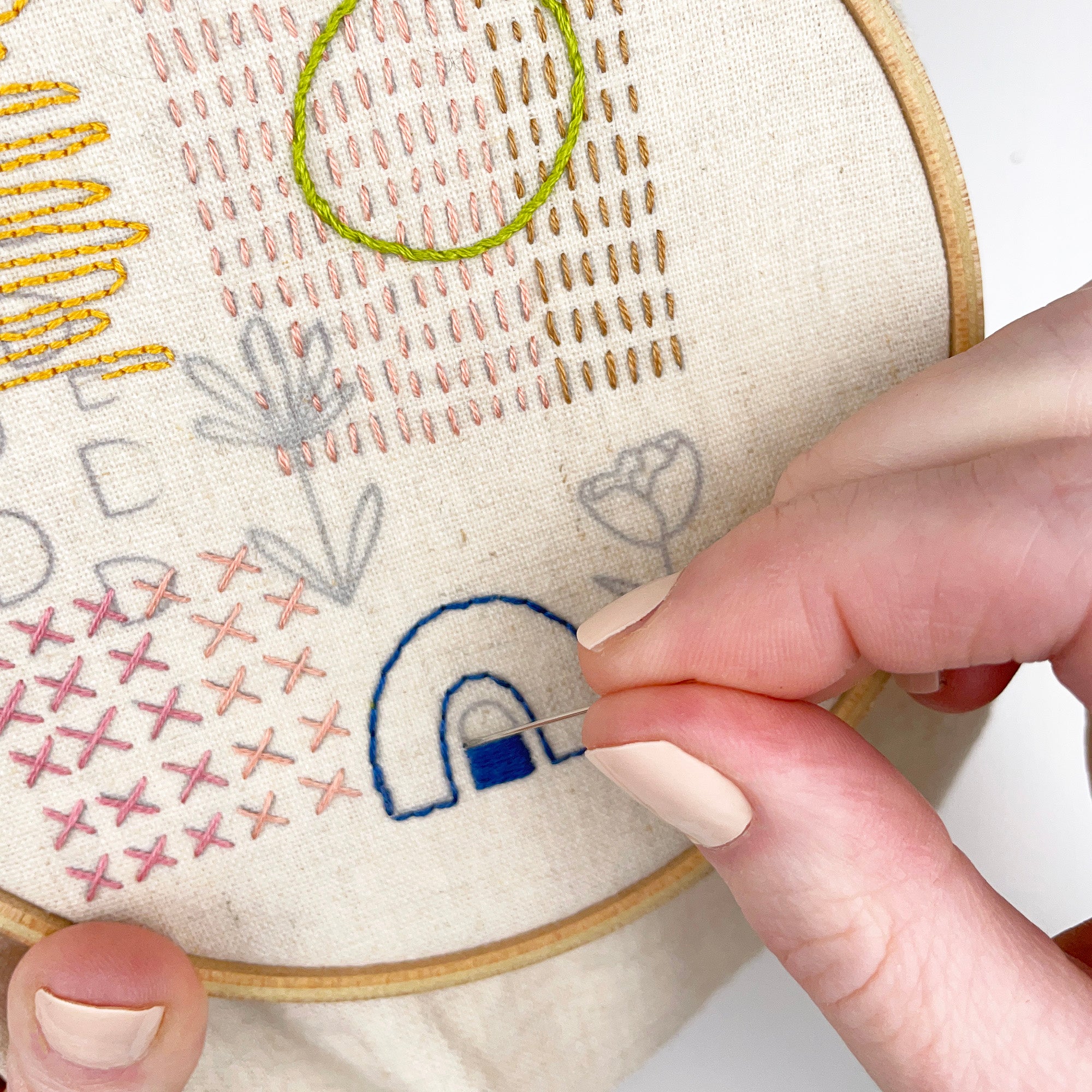 Hand stitching colorful embroidery patterns using Iron-On Embroidery Patterns: Slow Stitching Textures on fabric in hoop.