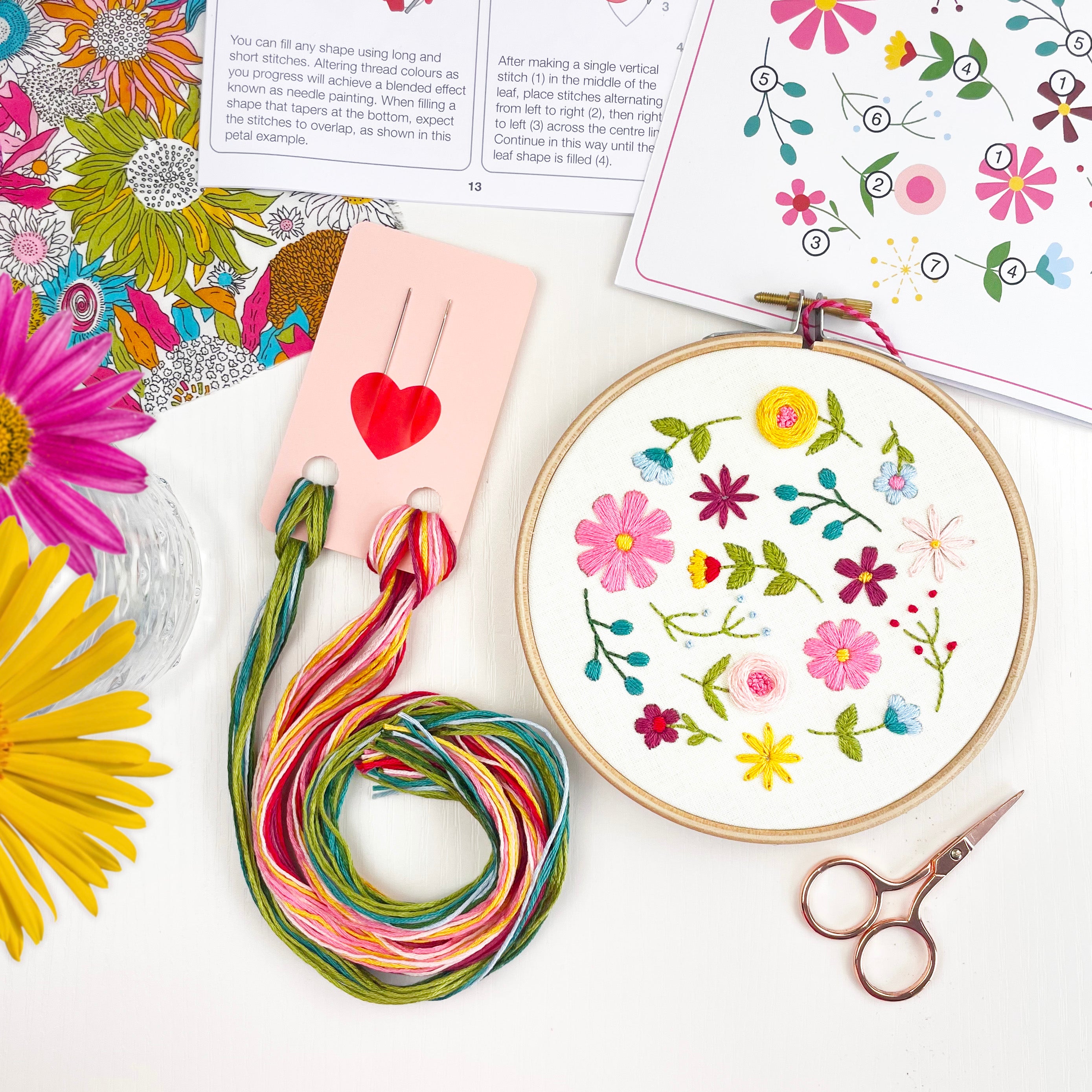 Flat lay of floral embroidery kit supplies including hoop, threads and printed instructions – beginner embroidery letterbox gift set.