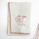 White towel with pink embroidered apples and 'Tomatoes' text on a white background