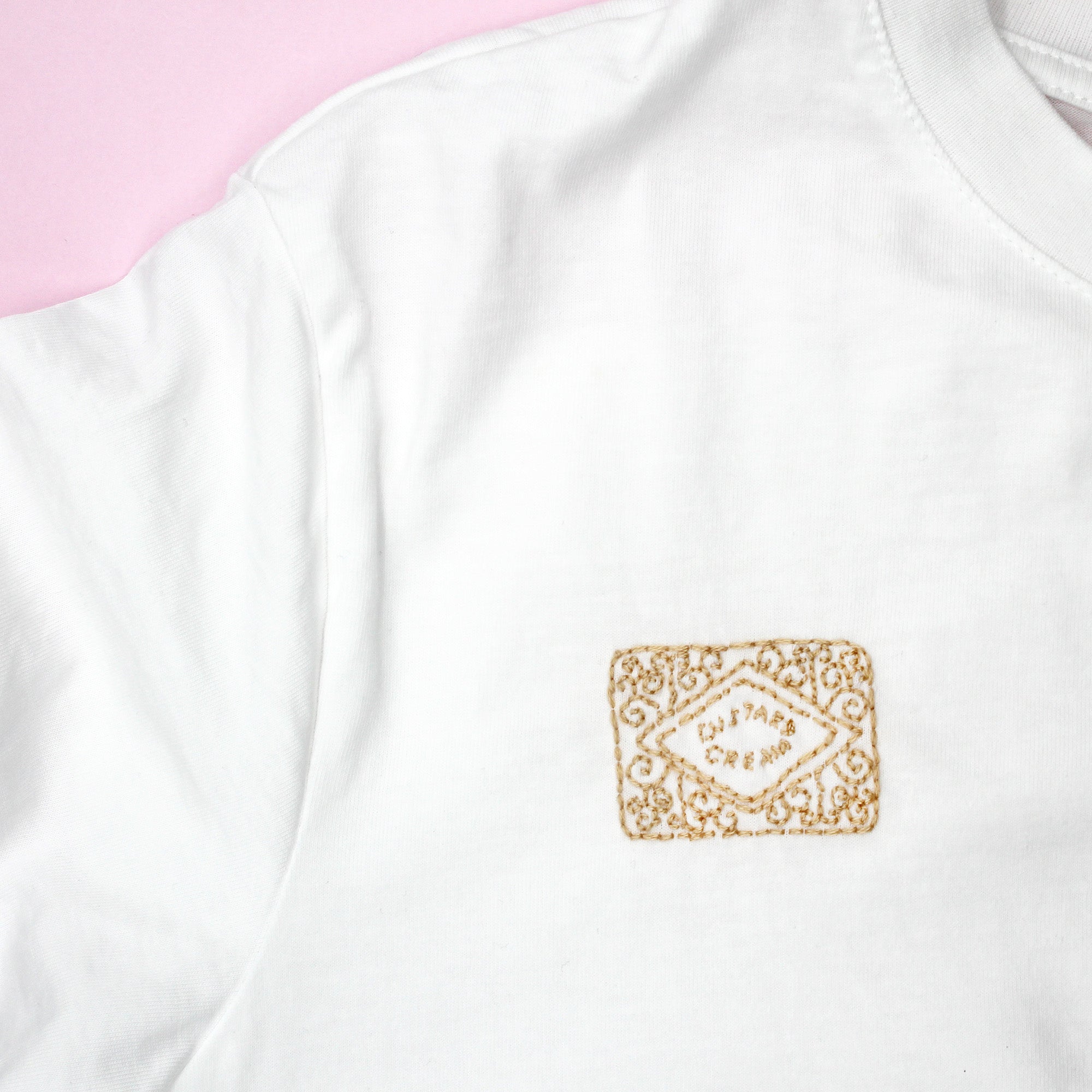 Embroidered custard cream biscuit design stitched onto a white T-shirt using a stick and stitch embroidery pattern. This modern embroidery pattern is perfect for customising clothing with dissolving embroidery designs.