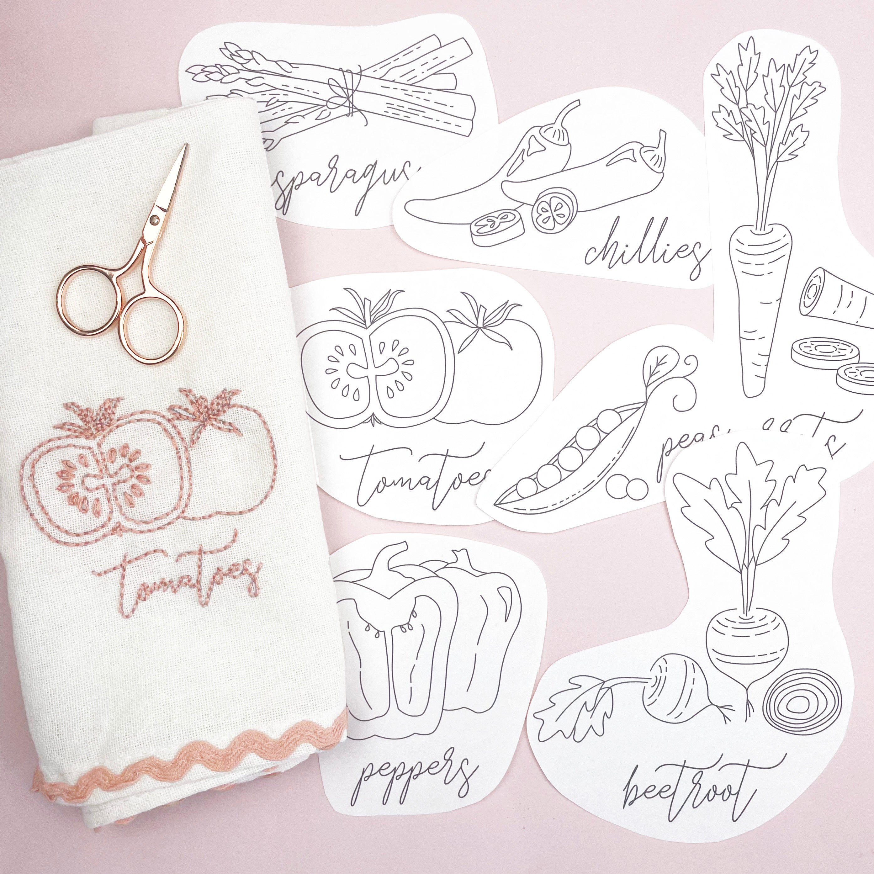 Set of vegetable-themed coloring sheets with a white towel and scissors on a pink background